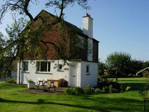 Cornhill-on-tweed的住宿－Orchard Cottage，前面有一张野餐桌的白色房子