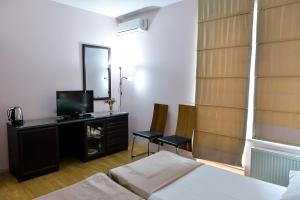 Imereti Health Resort في تسكالتوبو: غرفة نوم بسرير وتلفزيون ومرآة
