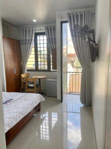 a bedroom with a bed and a table and a balcony at Jasmine Mini Hotel in Hue