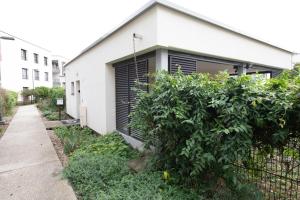 a white house with black shutter doors and a bush at La Villa et sa plume in Divonne-les-Bains +10 photos