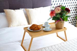 einen Couchtisch mit Croissants und einen Teller mit Essen auf dem Bett in der Unterkunft La Villa et sa plume in Divonne-les-Bains