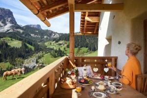 una donna seduta a un tavolo con cibo e vista su una montagna di Sotciastel Antico Chalet a Badia