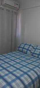 Bett mit blauer und weißer Decke in einem Zimmer in der Unterkunft Apartamento super aconchegante 150 da orla do bessa in João Pessoa
