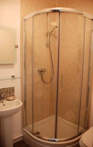 a shower with a glass door next to a sink at Wendover Guest House in Bolton