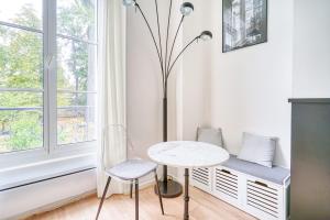 een witte tafel en stoel in een kamer met een raam bij La Reine Blanche in Dammarie-lès-Lys