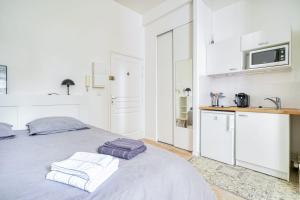 a white bedroom with a bed with towels on it at La Reine Blanche in Dammarie-lès-Lys