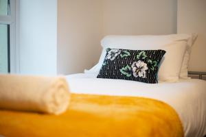 a bed with a black and white pillow on it at 2 Bathrooms, 5 Bedrooms, Available Parking in Port Talbot