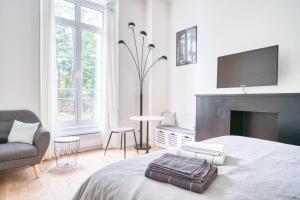 a bedroom with a bed with a tv and a chair at La Reine Blanche in Dammarie-lès-Lys