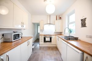 a kitchen with white cabinets and a sink and a microwave at Talbot Steel - Place to Stay! in Port Talbot