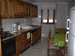 cocina con armarios de madera, fregadero y nevera en Casa Rural Laguao, en Abárzuza