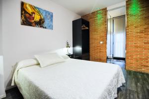 a bedroom with a white bed and a brick wall at Hotel Boutique Sabbia Valencia in Valencia