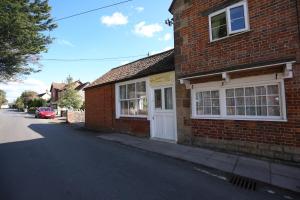 uma casa de tijolos com uma porta branca numa rua em The Annexe in Ditcheat em Ditcheat