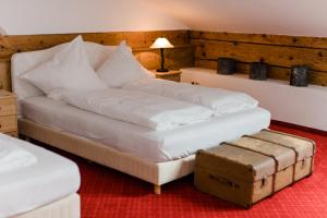 a bedroom with a large white bed with a trunk at Posthotel Sachrang in Sachrang