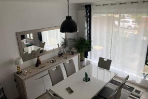 a dining room with a white table and chairs and a mirror at GITE SAINTE MARIE MADELEINE DOMONT 7 PERSONNES in Domont