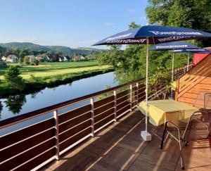 una mesa y una sombrilla en una cubierta junto a un río en Hotel Auermühle, en Hamm