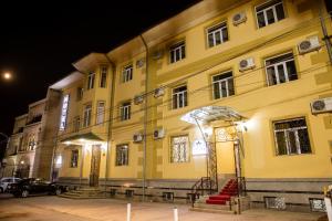 een groot geel gebouw 's nachts met een rode trap bij Stella Hotel Tashkent in Tasjkent