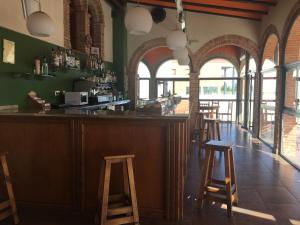 a bar with wooden stools in a room with windows at Hotel La Bodega in La Almunia de Doña Godina