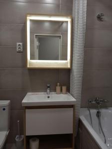 a bathroom with a sink and a mirror and a tub at Studio Galaxy 2 floor in Kyiv