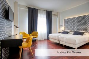 a hotel room with a bed and a desk and a table at Hotel Montermoso in Aranda de Duero