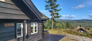 a cabin with a wooden deck next to a building at Gautefall- High-standard cozy cabin with indoors whirlpool-tub and sauna in Treungen