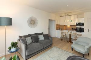 a living room with a gray couch and a kitchen at Cocoon Retreat in Chantilly