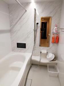 Baño blanco con bañera y lavamanos en クレアゲハウス新百合ケ丘 en Kawasaki