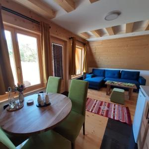 uma sala de estar com uma mesa de madeira e cadeiras verdes em Holiday Home Ella - Apartman Ella em Mokra Gora