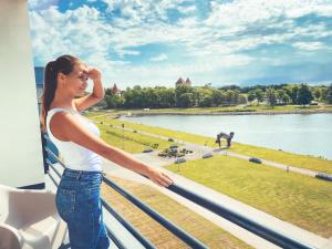 kobieta stojąca na balkonie z widokiem na park w obiekcie Ö Seaside Suites & SPA w mieście Kuressaare