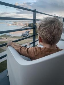 Ö Seaside Suites & SPA في كوريساري: صبي صغير يجلس على كرسي يطل على المحيط