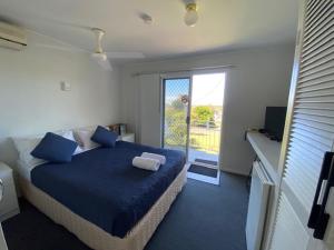 a bedroom with a bed with blue sheets and a window at Leisure-Lee Holiday Apartments in Ballina