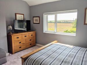 a bedroom with a bed and a tv and a window at Cottars in Winfrith Newburgh