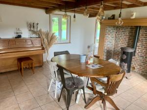 a dining room with a wooden table and a piano at Le gîte du bois Greffier in Flêtre