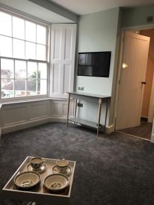 a living room with a tv and a tray of plates at Mount Street House in Brecon