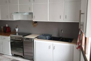 eine Küche mit weißen Schränken und einer Spüle und einem Herd in der Unterkunft Maison de ville Angoulêmoise in Angoulême