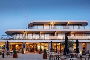 a building with tables and umbrellas in front of it at Duinhotel Breezand in Vrouwenpolder