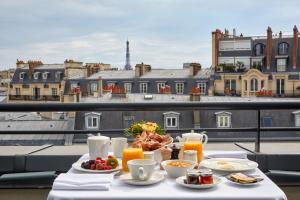 a table with breakfast food on a balcony with a view at Ampère in Paris