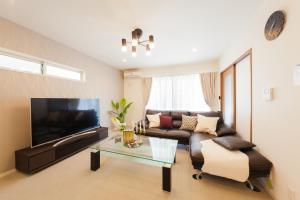 ein Wohnzimmer mit einem Sofa und einem Flachbild-TV in der Unterkunft Prestige Suites Osaka Kishinosato-Tamade in Osaka