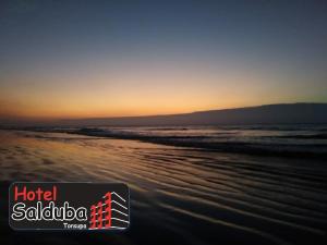 uma fotografia da praia ao pôr-do-sol com as palavras hotel saliba em Hotel Salduba em Tonsupa