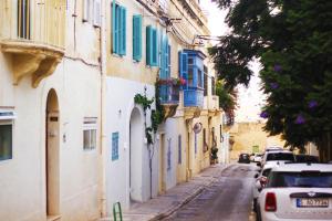 an alley with blue shutters and cars on a street at Giljana ensuite rooms shared terrace & kitchen in St. Julianʼs
