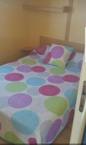 a bed with a polka dot blanket and a pillow at Casa Prefabricada in El Palmar
