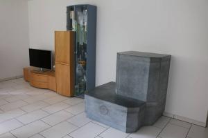 een woonkamer met een tv en een stenen bank bij Ferienwohnung für 5 Personen in Cumpadials, inmitten der Surselva in Sumvitg