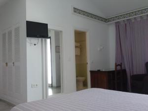 1 dormitorio con 1 cama y TV en la pared en Los Helechos, en Sanlúcar de Barrameda