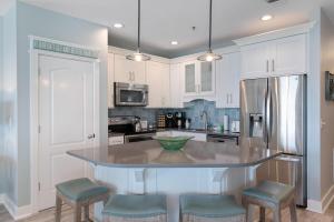 a kitchen with white cabinets and a island with stools at The Villas at Santa Rosa Beach in Santa Rosa Beach