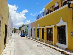 a street with a yellow building and a blue car at El Navegante in Campeche