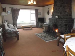 a living room with a stone fireplace and a window at Rose Cottage in Kilcrohane