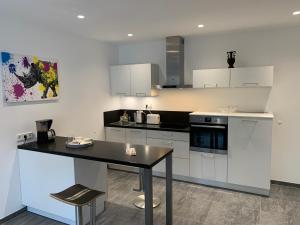 a kitchen with white cabinets and a black table at Gala Apartment am Kurpark in Bad Rothenfelde