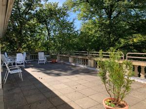 a patio with white chairs and a fence and trees at Gala Apartment am Kurpark in Bad Rothenfelde