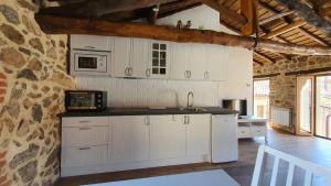 a kitchen with white cabinets and a stone wall at Casas del Castillo, 2 in Avila +6 photos