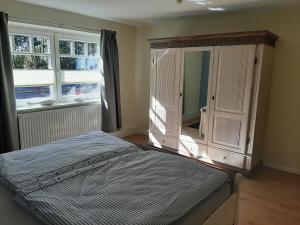 a bedroom with a bed and a cabinet and two windows at Ferienwohnung Hans & Elsa in Neudorf-Bornstein