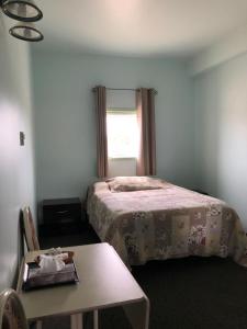 1 dormitorio con cama, mesa y ventana en IceBerg Inn, en Churchill